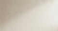 A light beige textured wall surface with subtle rough patches and soft light creating a warm, neutral background effect Royalty Free Stock Photo