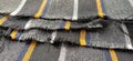 Light black-gray folded fabric with orange and dark blue stripes. Ripped, unfinished fabric edge. Interior decoration. Dress