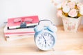 Light blue alarm clock on wooden table with books and glasses Royalty Free Stock Photo