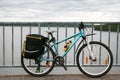 Light-blue all-terrain bicycle with pannier bags and yellow bottle standing infront of lake