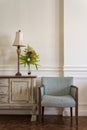 Light blue armchair and cream vintage sidebar with table lamp