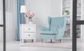 Light blue armchair and drawers cabinet with table lamp and flowers vase on it Royalty Free Stock Photo