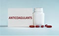 On a light blue background a card with the text ANTICOAGULANTS near the white bottle pills Royalty Free Stock Photo