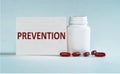 On a light blue background a card with the text PREVENTION near the white bottle pills Royalty Free Stock Photo