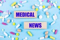 On a light blue background, multi-colored pills and wooden blocks with the text MEDICAL NEWS. Pharmaceutics. Medical concept Royalty Free Stock Photo