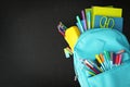 Light blue backpack with different stationery on blackboard, top view and space for text. Back to school Royalty Free Stock Photo