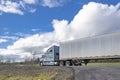 Light blue big rig industrial semi truck transporting cargo in dry van semi trailer driving on the local narrow road with cloudy Royalty Free Stock Photo