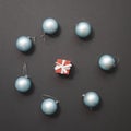 Light blue Christmas balls lie around a small red gift box against a dark background. New Year mockup Royalty Free Stock Photo