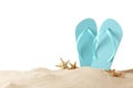 Light blue flip flops and starfishes on sand against background, space for text. Beach objects Royalty Free Stock Photo