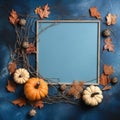 Light blue frame with pumpkins, dry fall leaves, dry twigs on blue textured background.