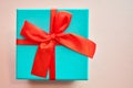 Light blue gift box with a red bow on a pink background. Royalty Free Stock Photo