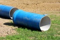 Light blue large diameter construction pipes left on construction site surrounded with grass and dry soil Royalty Free Stock Photo
