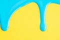 Light blue liquid drops of paint color flow down on yellow paper background. Blue paint dripping on the yellow wall with copy Royalty Free Stock Photo