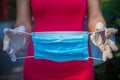Light blue medical mask demonstration. Hands in white gloves. Female silhouette in red dress out of focus in background