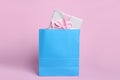 Light blue paper shopping bag with gift box on pink background Royalty Free Stock Photo