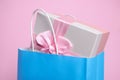 Light blue paper shopping bag with gift box on pink background, closeup Royalty Free Stock Photo