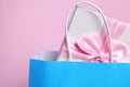 Light blue paper shopping bag with gift box on pink background, closeup. Space for text Royalty Free Stock Photo