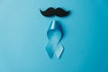 Light blue ribbon with mustache on blue background. Healthcare, International men, Father and World cancer day concept. Royalty Free Stock Photo