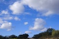 Beautiful blue sky with big white clouds, line of land with green trees and bushes. Seville, Spain