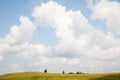 Light blue sky with fluffy clouds and subltle path on green summer hill with trees landscape Royalty Free Stock Photo