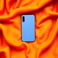 Blue phone on vibrant orange fabric textile draped Royalty Free Stock Photo