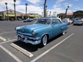 Light blue and white 1950s Ford Crestline in parking lot - front driver side view