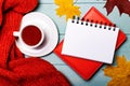 On a light blue wooden background, an orange sweater, autumn maple leaves, a white cup of tea, and a white blank notepad. Copy Royalty Free Stock Photo