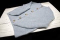 Light Blue Woollen Cardigan with tortoiseshell buttons round necked and laid out on a white wooden board