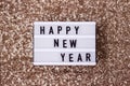 Light board inscription new year on a gold sequin background. Winter holiday Royalty Free Stock Photo