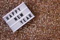 Light board inscription new year on a gold sequin background. Winter holiday. Copy space Royalty Free Stock Photo