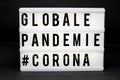 A light box with the inscription: GLOBALE PANDEMIE #CORONA with white background Royalty Free Stock Photo