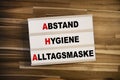 Light box or lightbox with the german acronym AHA - Abstand, Hygiene, Alltagsmaske on wooden background