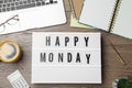 Light box with message Happy Monday, office stationery and cup of coffee on wooden desk, flat lay Royalty Free Stock Photo