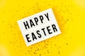 Light box over bright yellow background with the text Happy Easter. Easter celebration concept. Golden eggs and stars Royalty Free Stock Photo