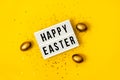 Light box over bright yellow background with the text Happy Easter. Easter celebration concept. Golden eggs and stars confetty Royalty Free Stock Photo