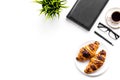 Light breakfast of businessman. Coffee and croissant near notebook and glasses on white background top view copy space