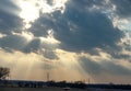 Light breaking through clouds over highway with cars at twilight with electric towers with factory in background