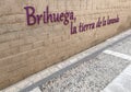 A light brick wall with the Spanish slogan Brihuega the land of lavender, festival or fair of lavender, on a medieval paved street