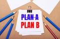 On a light brown background, blue and red pencils and white paper with the text PLAN B Royalty Free Stock Photo