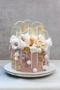 Light brown and golden colored birhtday cake with macaroons, coins, meringue and lollipops Royalty Free Stock Photo