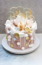 Light brown and golden colored birhtday cake with macaroons, coins, meringue and lollipops Royalty Free Stock Photo