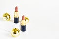Light brown lipsticks on a white background with Christmas golden balls . Christmas gift for women. Festive decoration of cosmetic