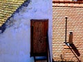 Light brown sloped clay roof with stack and white gable end wall with old brown access door Royalty Free Stock Photo