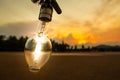 Light bulb on the beach and mountain background,lamp light with sunset,energy conceptLight bulb on the beach and mountain
