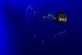 Light bulb with burning filament lay on blue surface with reflection Royalty Free Stock Photo