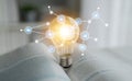 Light Bulb with Connected Digital Icons Over an Open Book Representing Innovative Ideas and Knowledge Exchange in a Royalty Free Stock Photo