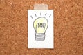 Light bulb drawn on white paper on cork board. Royalty Free Stock Photo