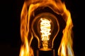 Light bulb with fire flames around it on a black background Royalty Free Stock Photo