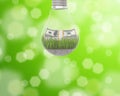 Light bulb with grass and a wad of dollars inside on green background Royalty Free Stock Photo