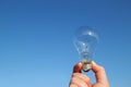 Light bulb and the hand in the blue sky Royalty Free Stock Photo